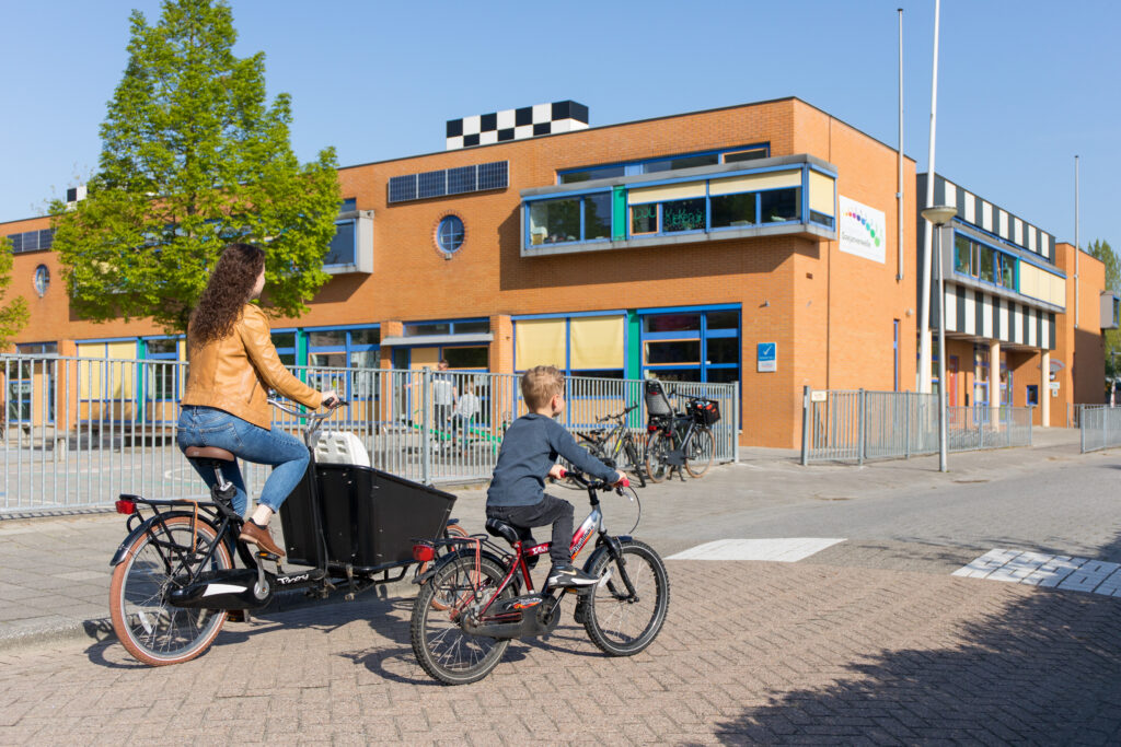 Foto van vrouw en kind die naar school fietsen.